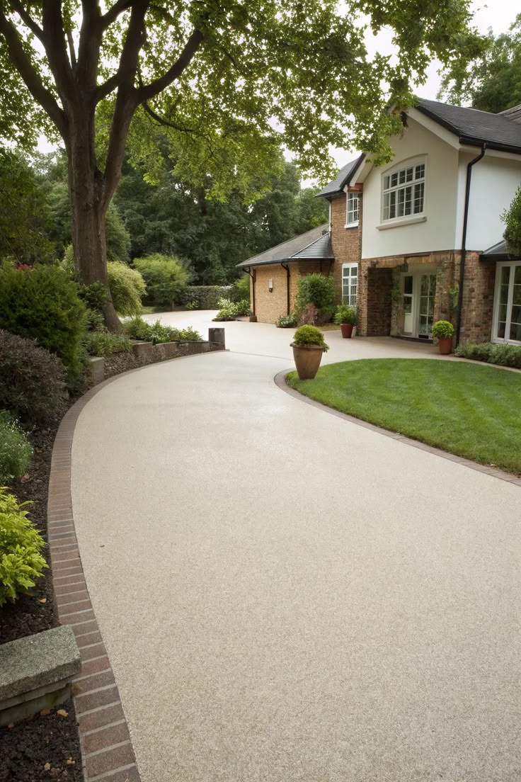 Sweeping pale resin driveway beside landscaped gardens